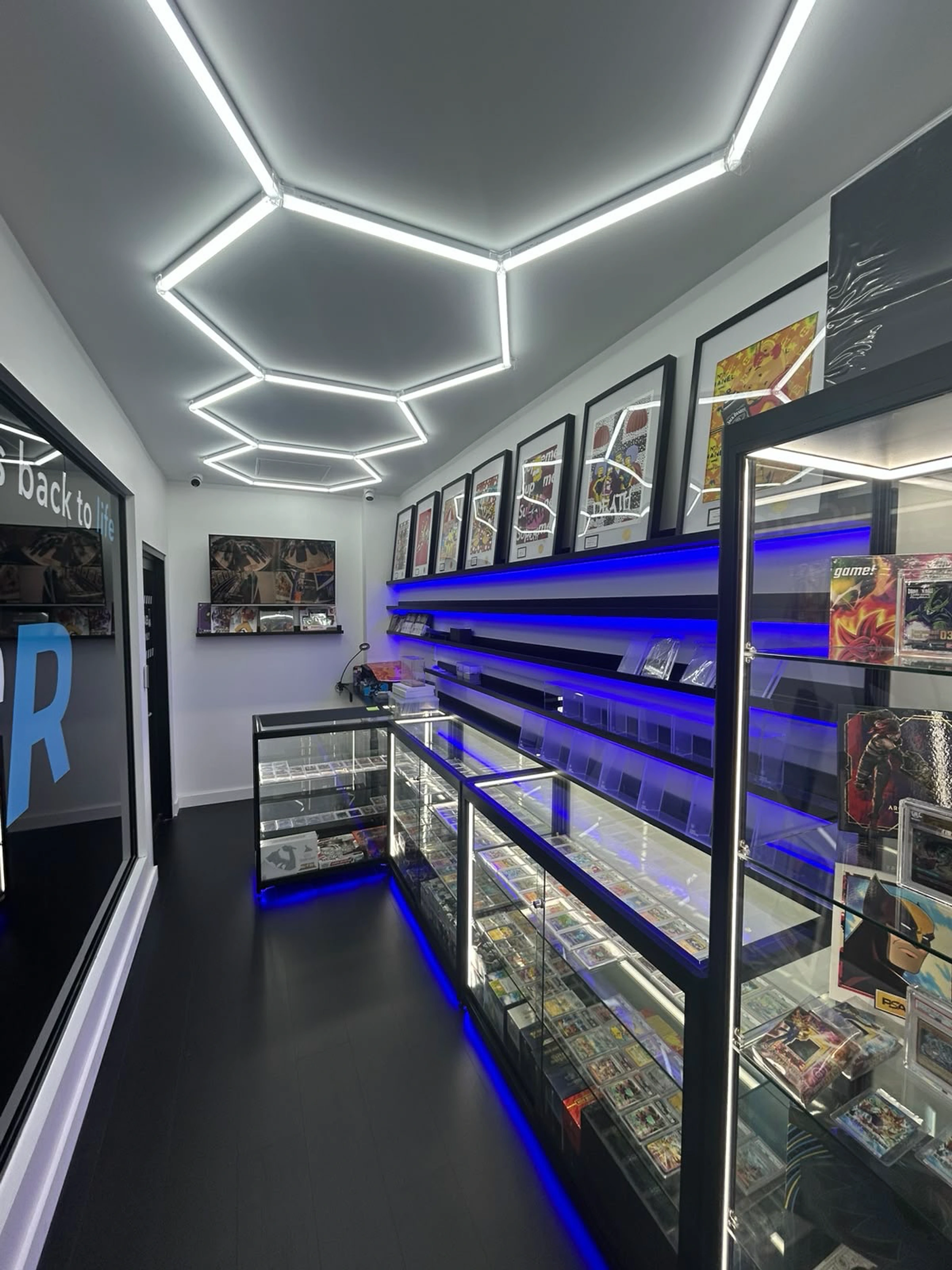 Inside the CardRevive collector shop with illuminated display counters, wall shelving and framed card artwork.