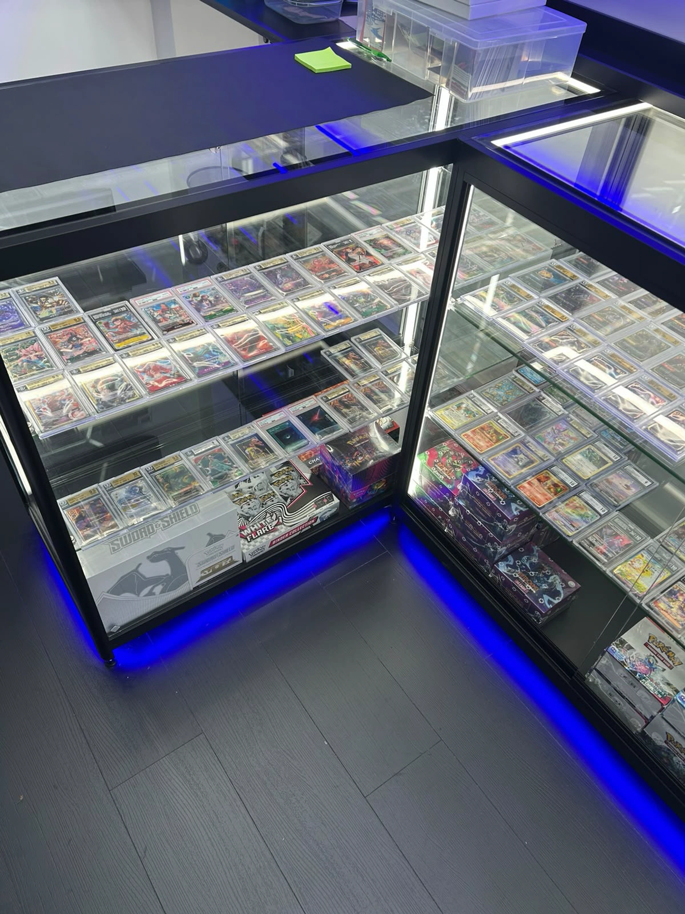 Illuminated glass counters displaying graded trading cards, singles and sealed products inside CardRevive.