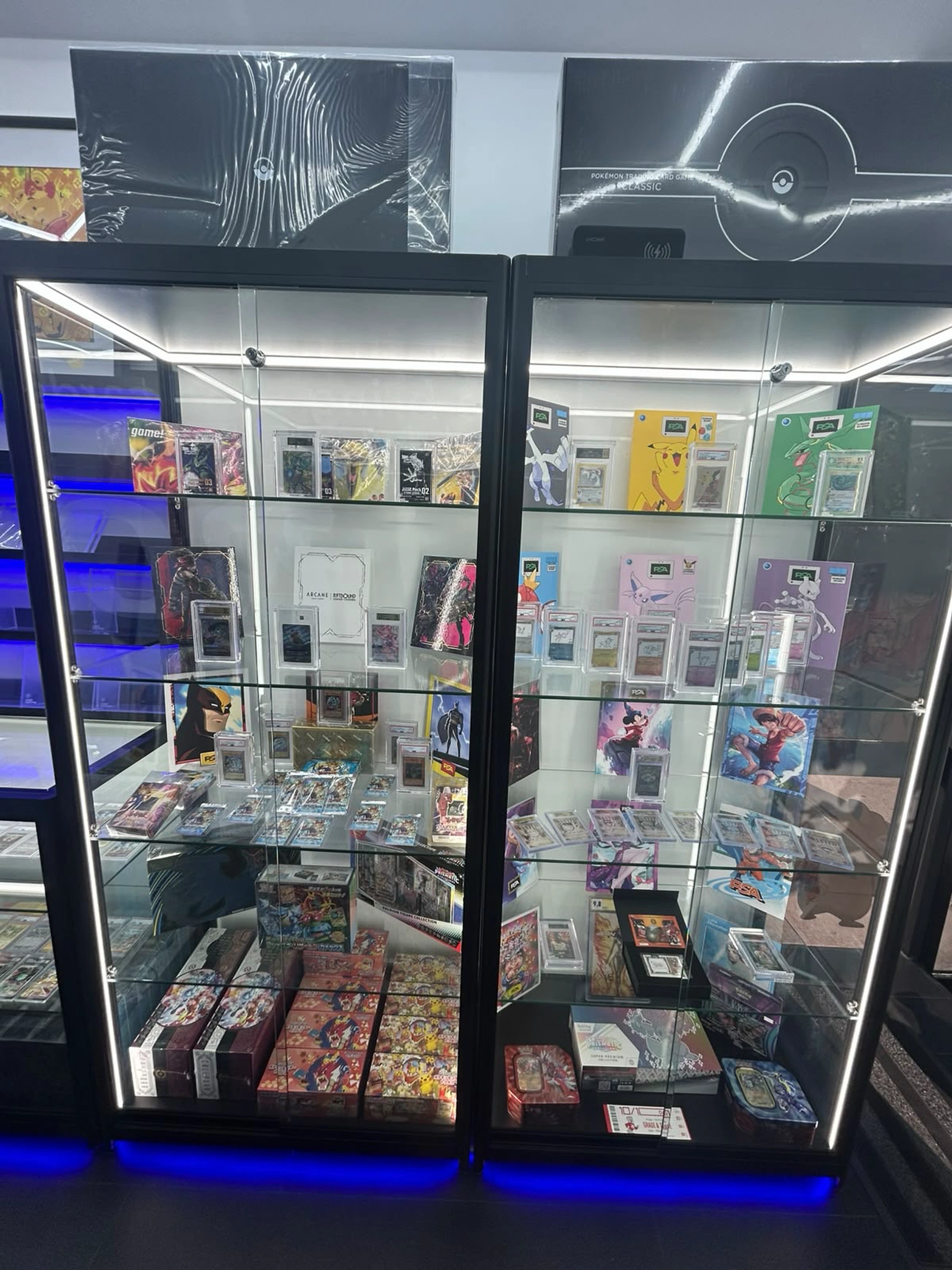 Lit display cabinets containing graded cards, sealed trading card products and collector pieces at CardRevive.