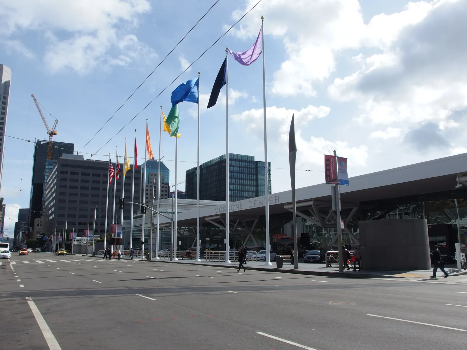 The Moscone Center in San Francisco seen from across the street, with a row of flagpoles along the footpath.