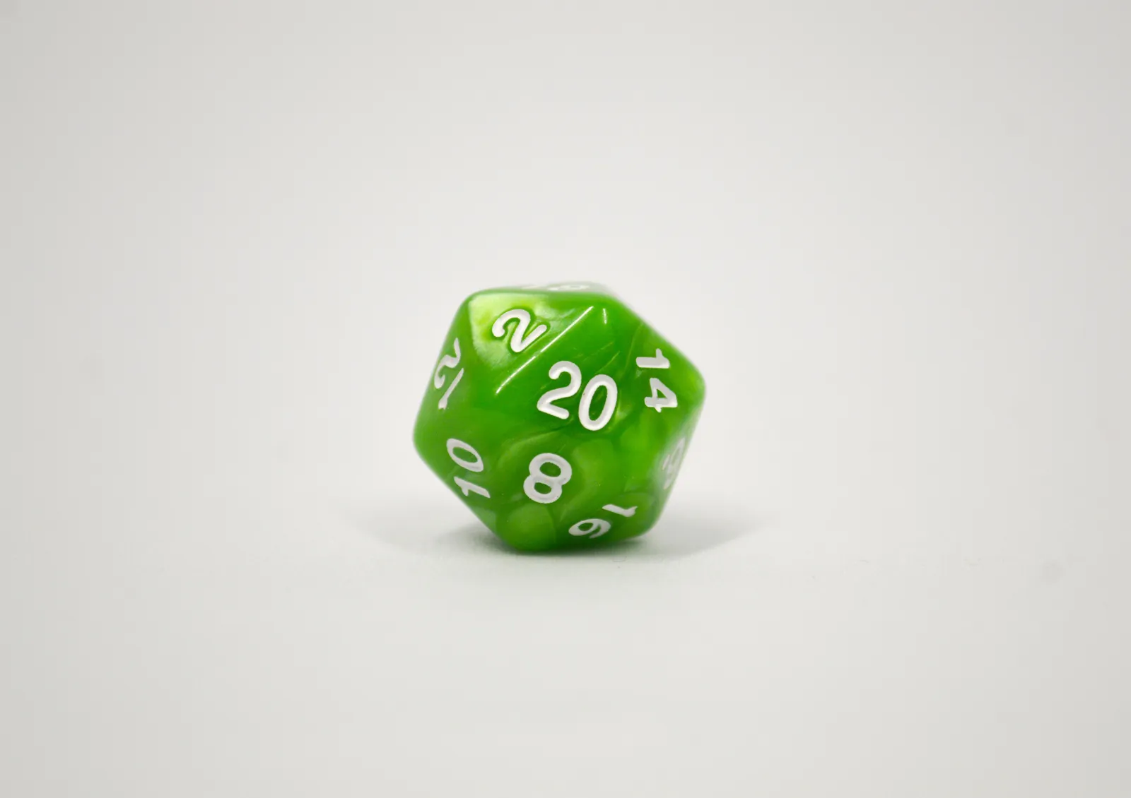A single green twenty-sided die resting on a plain white surface.