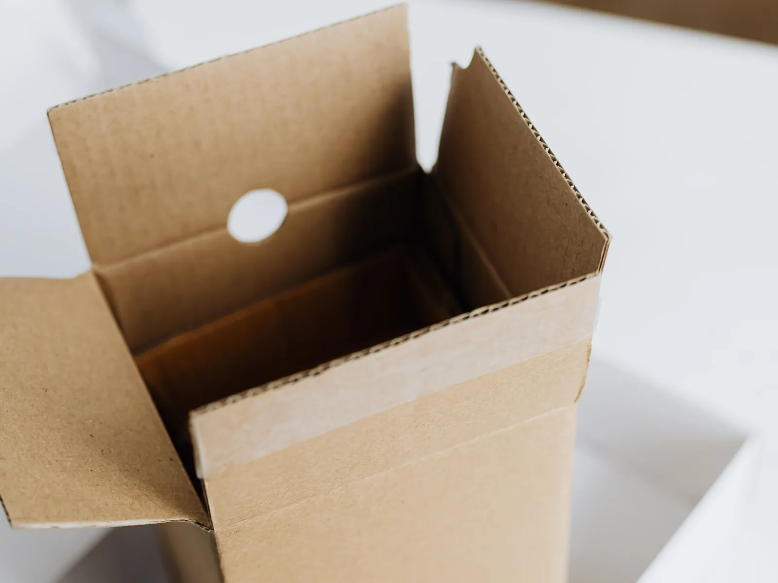 An open cardboard shipping box with its flaps folded back on a table, ready for packing or unpacking.