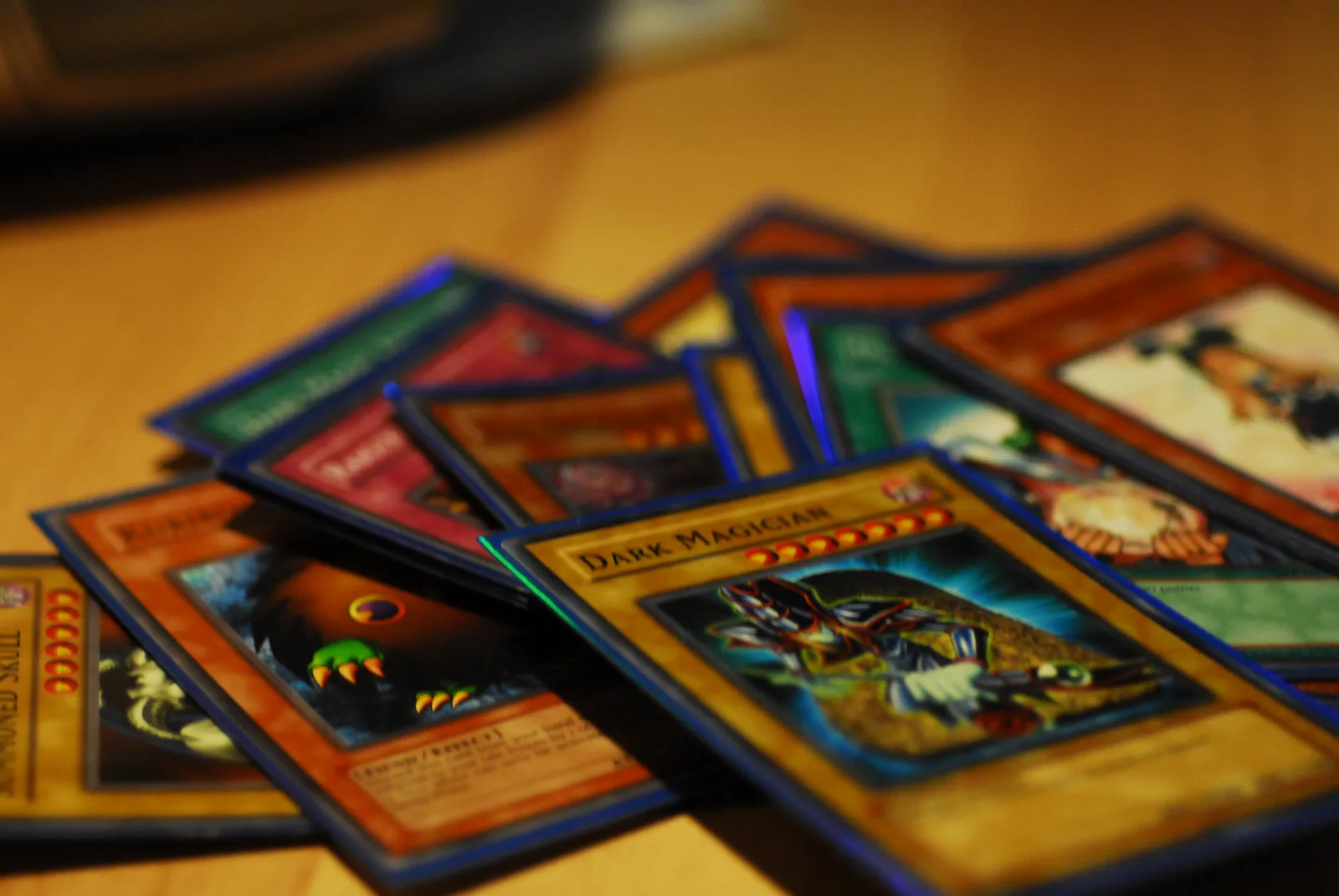 A hand of vintage Yu-Gi-Oh! trading cards fanned out on a wooden table, including a visible Dark Magician card.