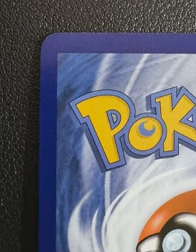Close-up of a Pokemon card back corner after CardRevive corner correction, sitting square with an even border