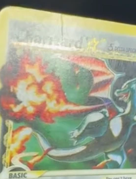 Holographic Charizard trading card with a visible crease line running across the top of the card before crease reduction